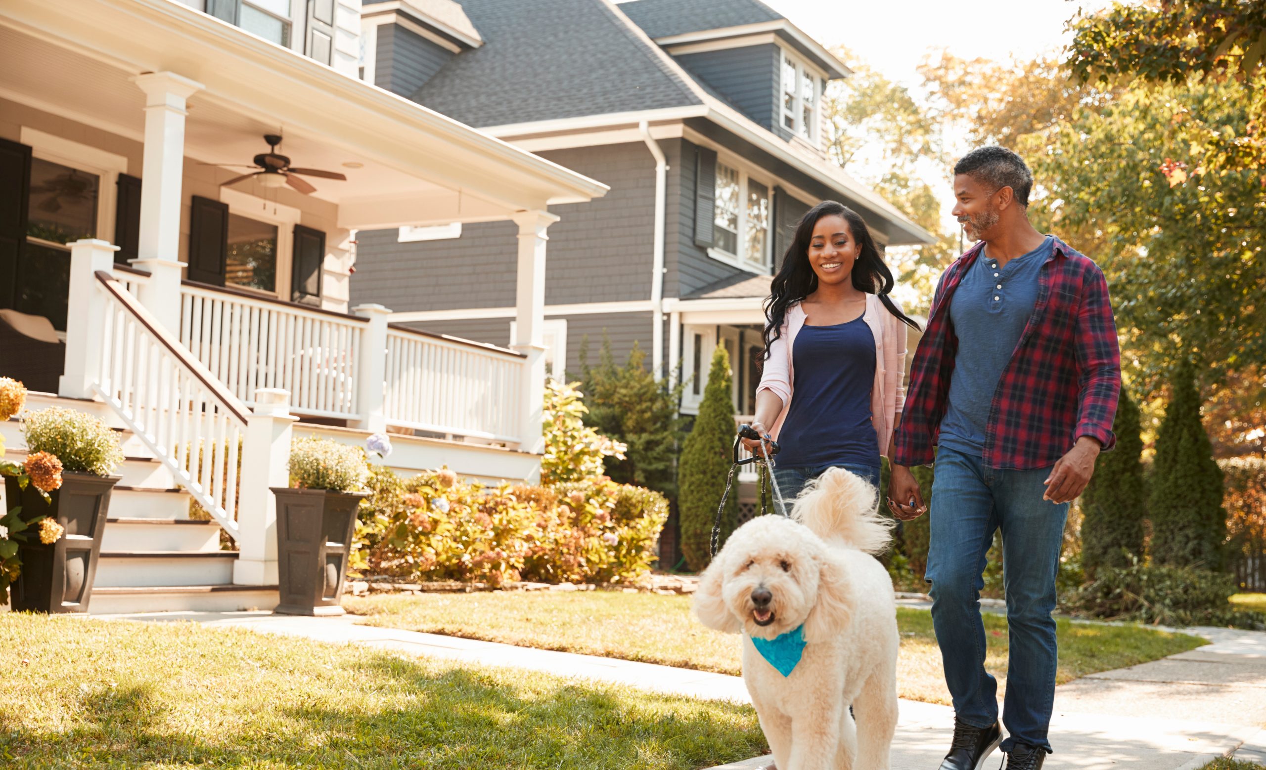 Couple Walking Dog Along Suburban Street