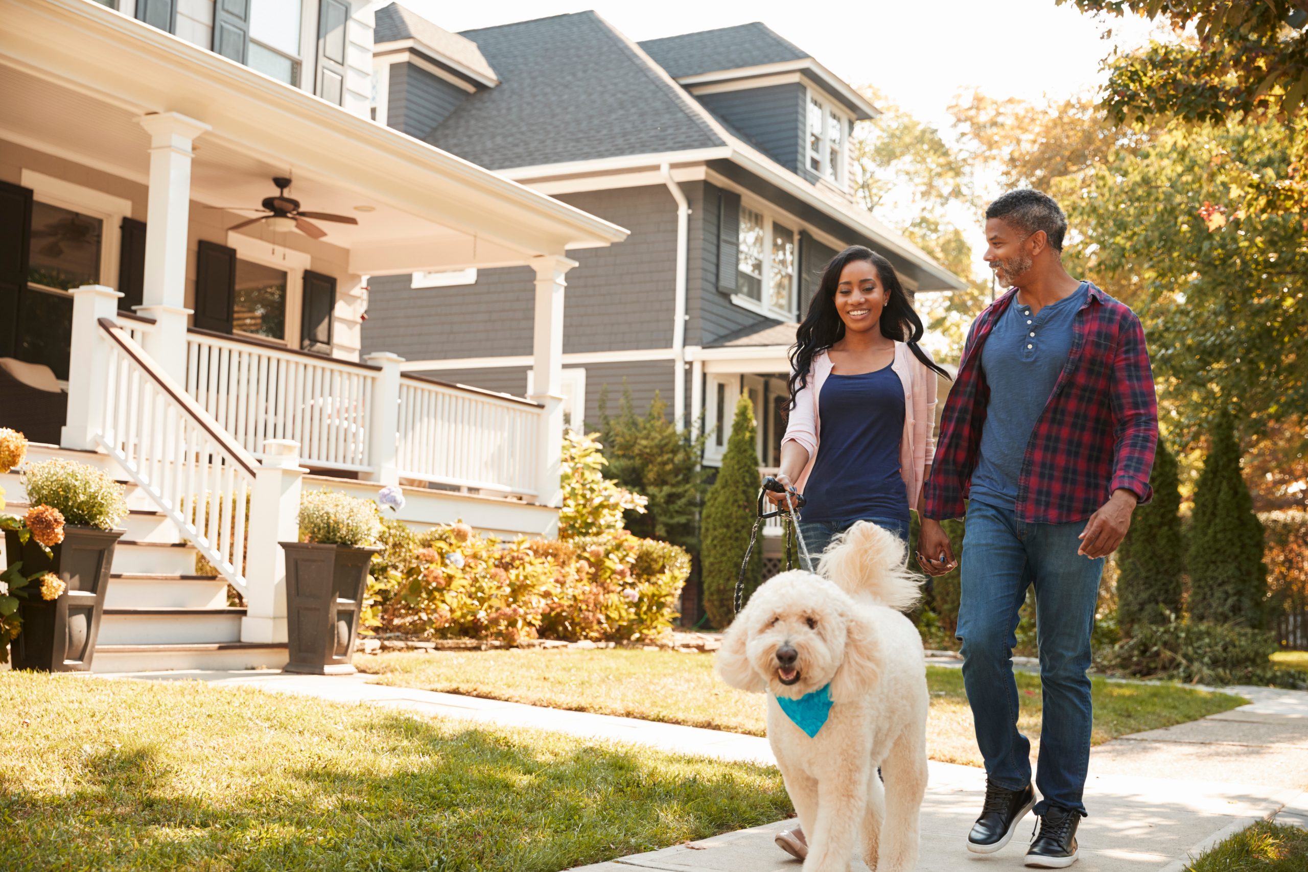 Couple Walking Dog Along Suburban Street